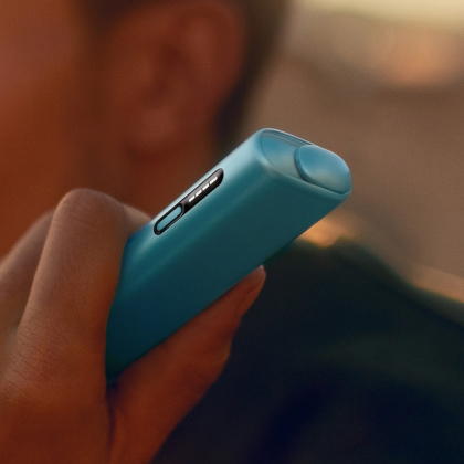 A person holding a Breeze Blue IQOS ILUMA i ONE.